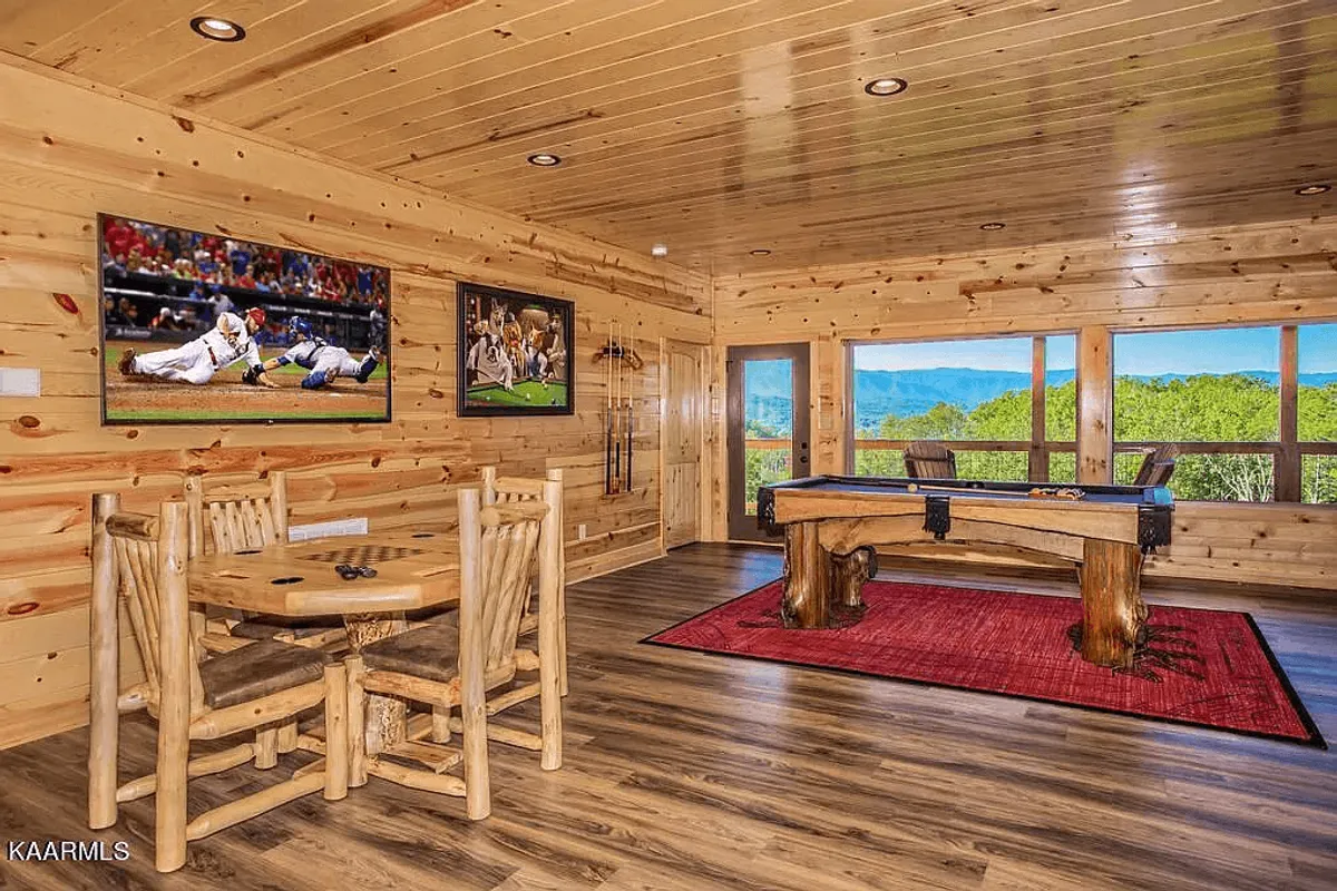 Inside, this room features a pool table, a dining table for group meals, large windows with views, and wall-mounted televisions. The space is clearly designed for entertainment and social gatherings, perfect for game nights and shared experiences.