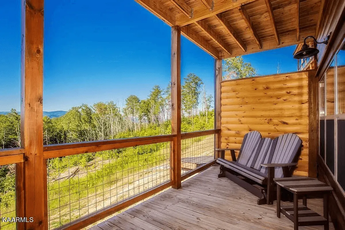 This image shows a spacious wooden deck outfitted with Adirondack chairs, offering a sweeping view of the mountains and lush surroundings. The deck is an inviting spot for guests to gather, socialize, or enjoy the beauty of nature together.