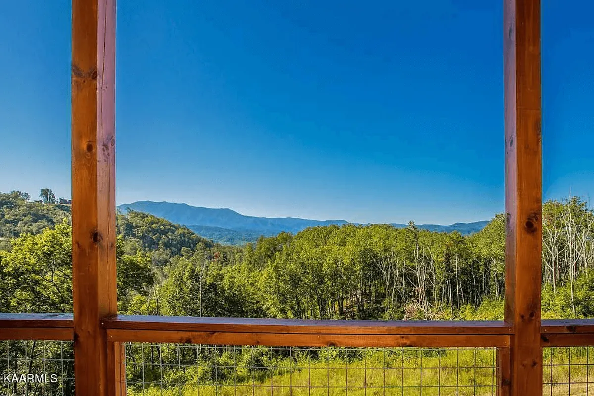 A breathtaking view of a mountain range framed by lush greenery and an expansive clear blue sky. The scene invites exploration and offers a sense of adventure and tranquility, with hints of activities like hiking or relaxing outdoors.