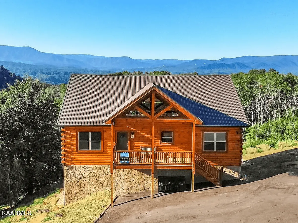 This image showcases the welcoming log cabin structure with a spacious porch set against a picturesque mountain backdrop. The porch invites guests to relax and take in the tranquil surroundings, while the broad view outward hints at the adventures and luxury experiences waiting both onsite and nearby.